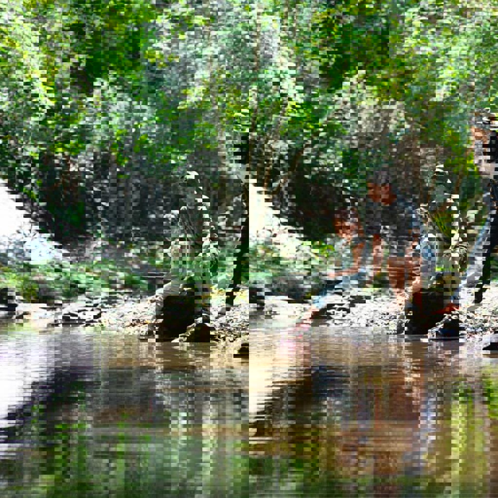 A group of people sitting on a log in a river.
