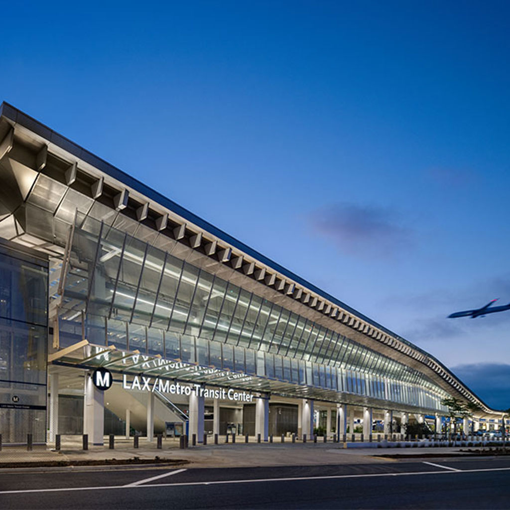 A large transit center at the airport with a plane flying by