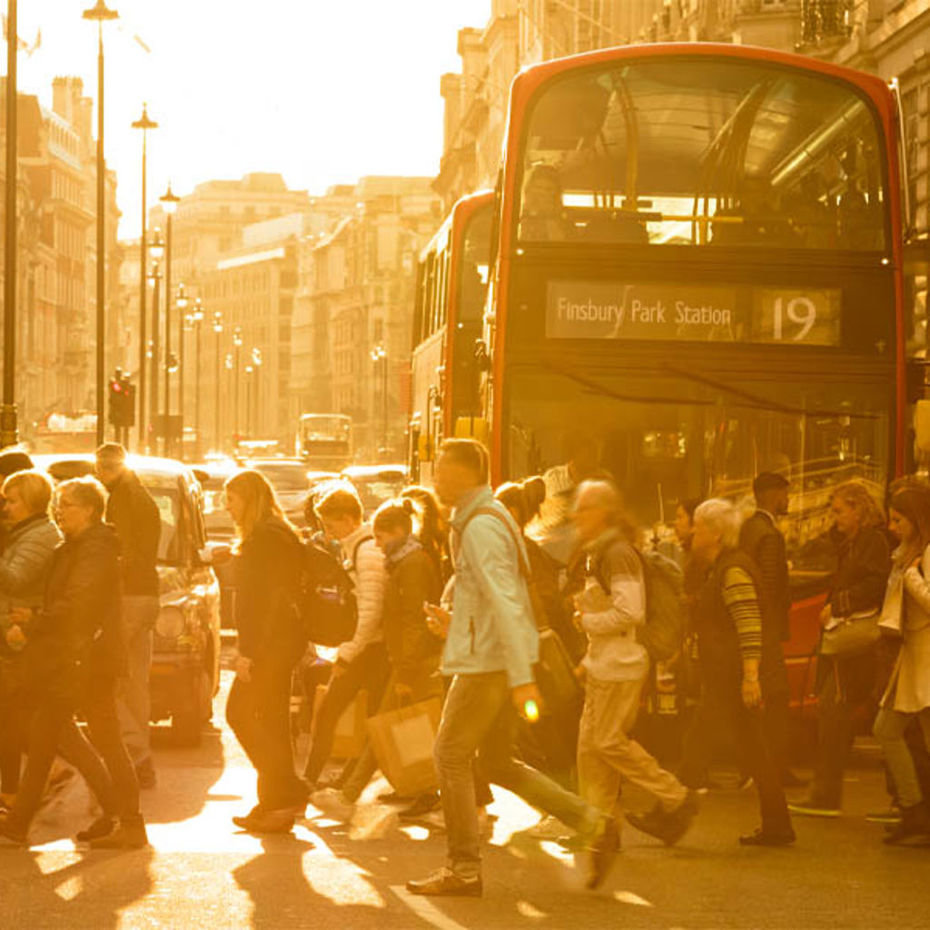 A group of people walking on a street next to a double decker bus.