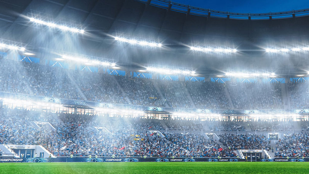 View from field of soccer stadium at night with crowd in distance and bright lights