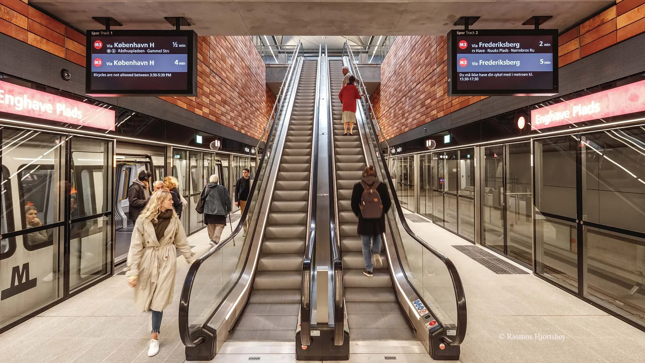 People walking down a escalator on a Cityringen station