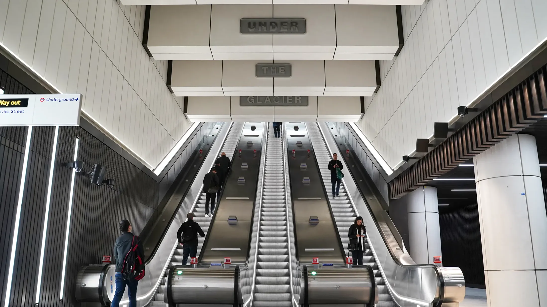 People using an escalator and station artwork at Bond Street