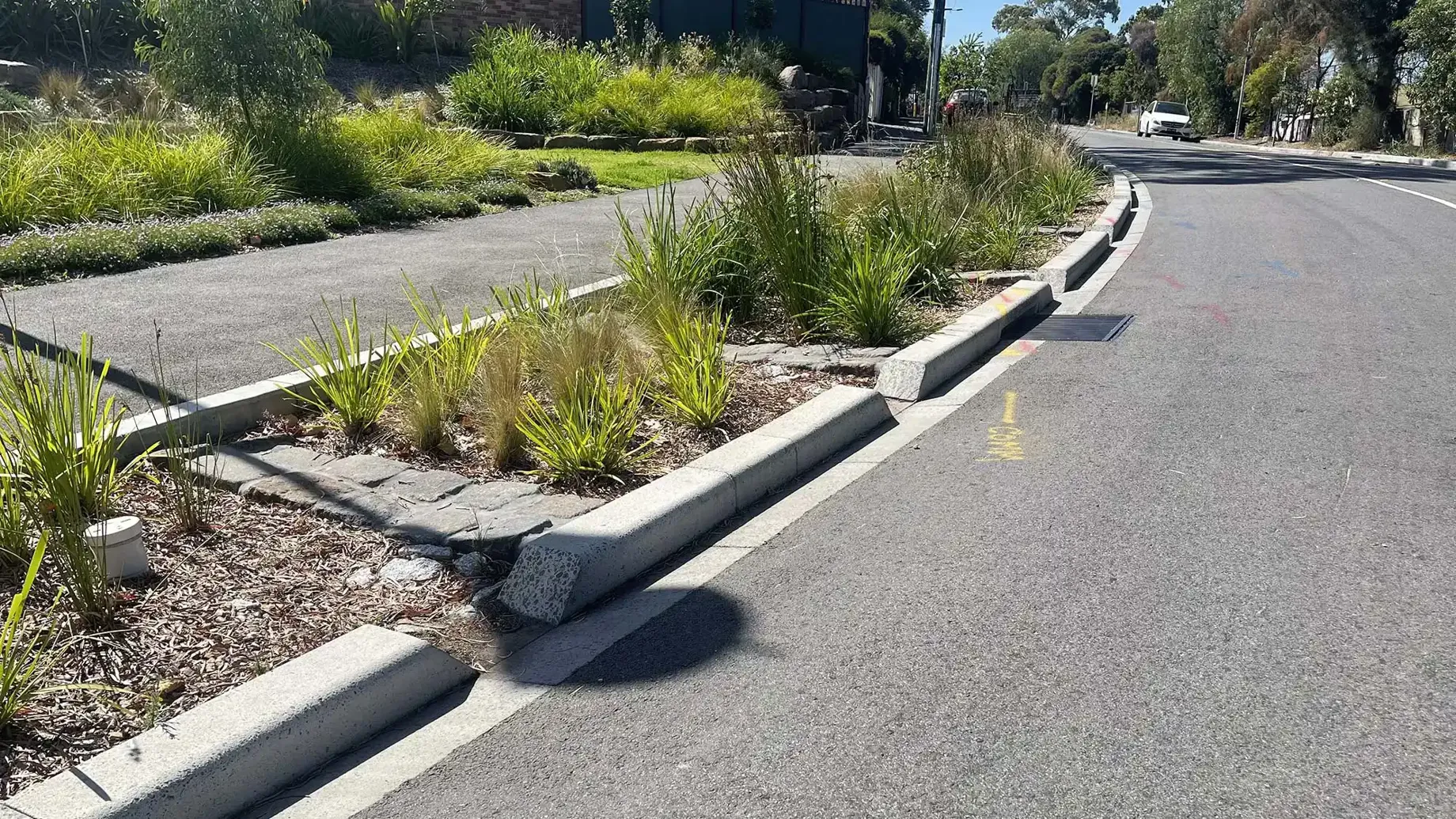 Extended curb with garden bed with pavers, pebbles and plants